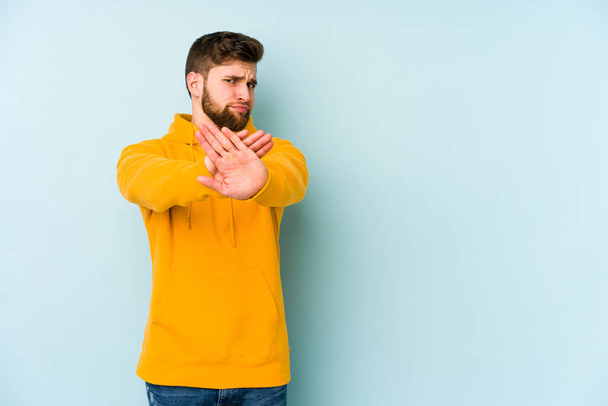 Young caucasian man isolated on blue background doing a denial gesture - Photo, Image