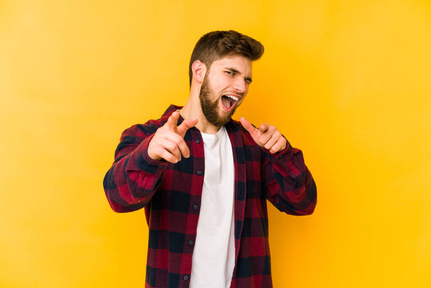 Young caucasian man isolated on yellow background pointing to front with fingers. - Photo, Image