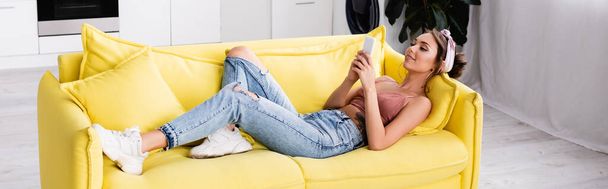 Imagen horizontal de la mujer acostada en el sofá y mirando el teléfono inteligente - Foto, Imagen