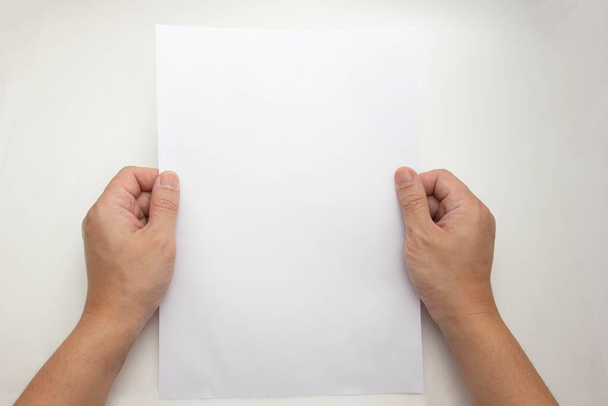Het concept van beide handen dat het vasthouden van een wit vel a4 van papier leeg op een witte achtergrond.Blanco papier voor uw brief. - Foto, afbeelding