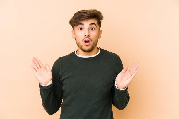 Young arabian man isolated on a beige background surprised and shocked. - Photo, Image