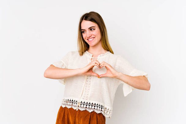 Jeune femme caucasienne isolée sur fond blanc souriant et montrant une forme de coeur avec les mains. - Photo, image