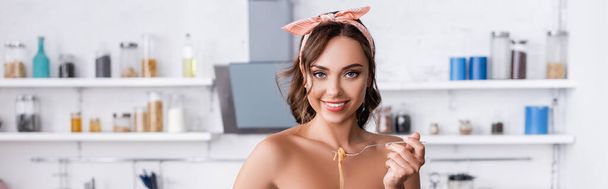 Website header of young woman looking at camera while holding spaghetti on fork at home  - Photo, Image