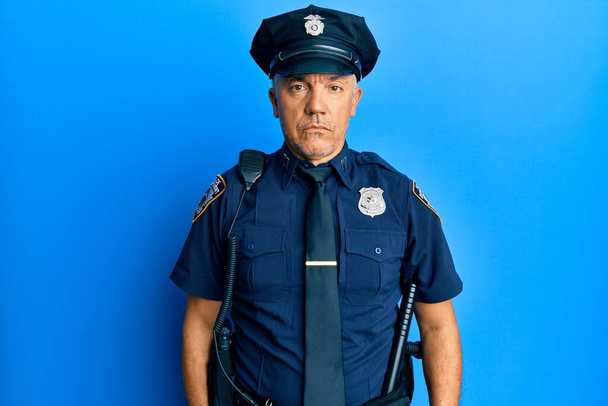 Pohledný dospělý muž středního věku v policejní uniformě se uvolnil s vážným výrazem ve tváři. jednoduchý a přirozený pohled do kamery.  - Fotografie, Obrázek