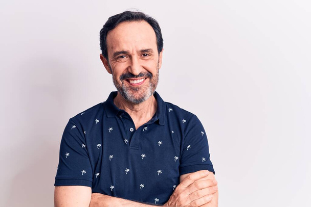 Middle age handsome man wearing casual polo standing over isolated white background happy face smiling with crossed arms looking at the camera. Positive person. - Foto, Bild