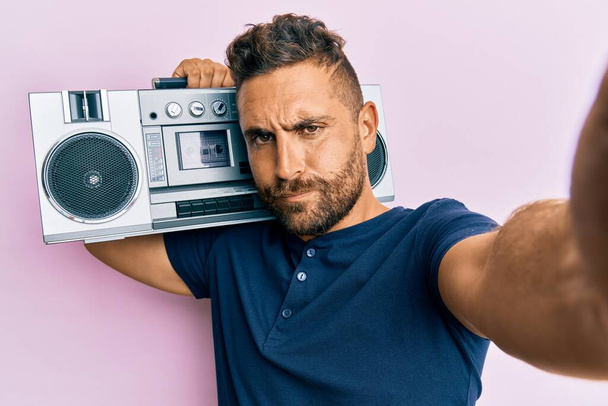 Handsome man with beard holding boombox, listening to music skeptic and nervous, frowning upset because of problem. negative person.  - Photo, Image