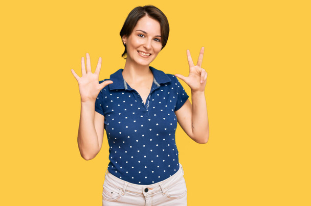 Young brunette woman with short hair wearing casual clothes showing and pointing up with fingers number eight while smiling confident and happy.  - Фото, зображення