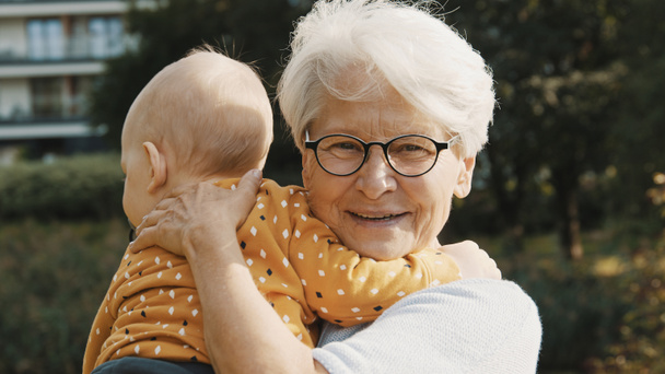 κοντά, ευτυχισμένη γιαγιά αγκαλιάζει τον εγγονό της στη φύση - Φωτογραφία, εικόνα