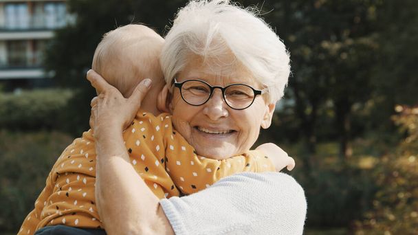 Happy grandmother holding her grandson baby in the nature - Photo, Image