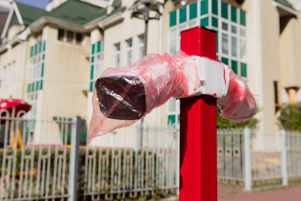 Two new white surveillance cameras in plastic bags on the red metal post. Installation of protection after construction. Closeup. - Photo, Image