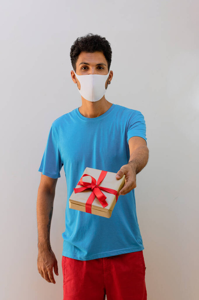 Muž černý s pandemickou maskou drží dar izolované bílé pozadí - Fotografie, Obrázek