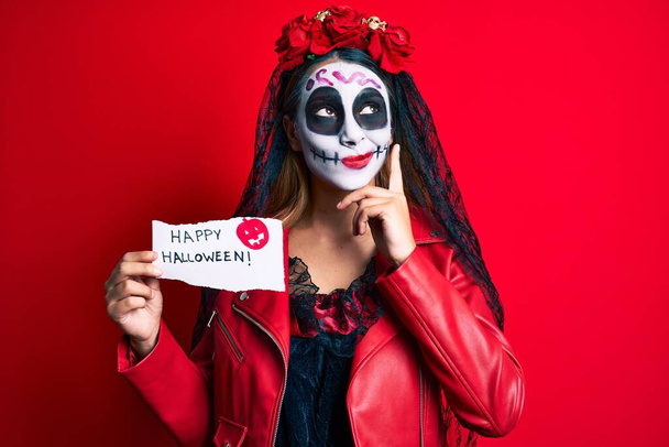 Жінка, одягнена в день мертвих костюмів, тримає щасливий папір на Хеллоуїн серйозне обличчя, думаючи про питання з рукою на підборідді, вдумливо про заплутану ідею
  - Фото, зображення