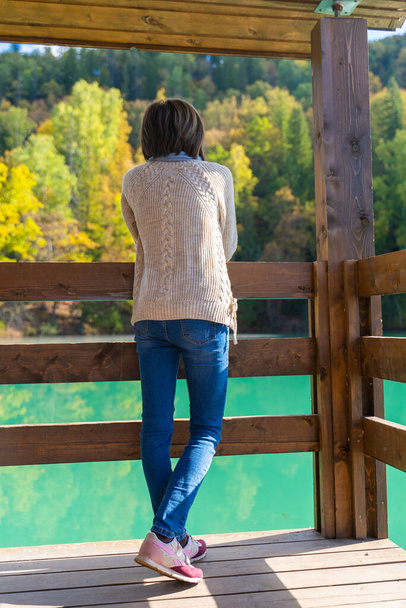A girl by a blue mountain lake with a house. Beautiful autumn morning - Photo, Image