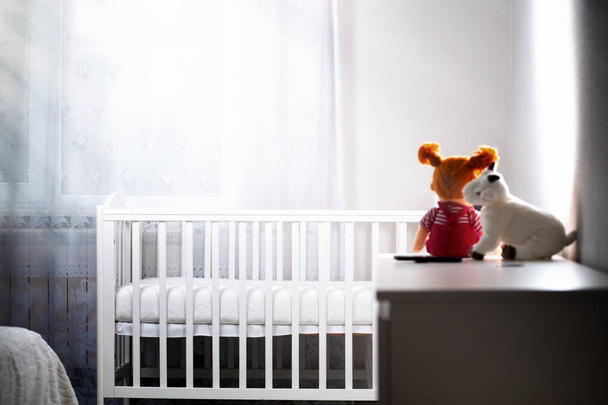 Kinderzimmer mit leerer Wiege und Spielzeug auf der Kommode. Kopierraum. Das Konzept der Abtreibung und weiblichen Unfruchtbarkeit. - Foto, Bild