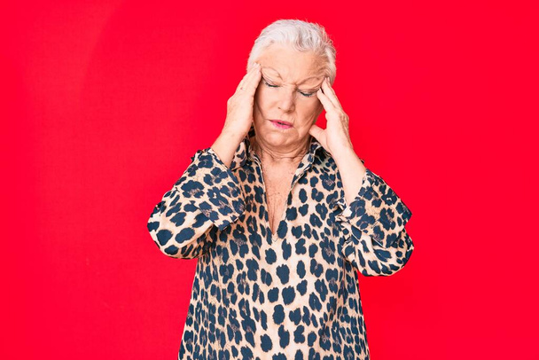 Ältere schöne Frau mit blauen Augen und grauen Haaren trägt lässig und modern Leoparden Animal Print Shirt leiden unter Kopfschmerzen verzweifelt und gestresst, weil Schmerzen und Migräne. Hände auf den Kopf.  - Foto, Bild