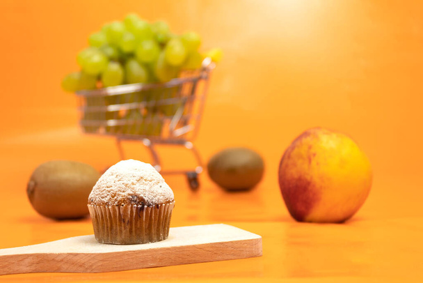 Čerstvý muffin sypaný práškovým cukrem. Pozadí textu. Čerstvé ovocné muffiny a ovoce - Fotografie, Obrázek