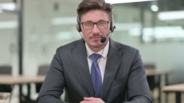 Retrato de hombre de negocios de mediana edad con auriculares mirando a la cámara  - Imágenes, Vídeo