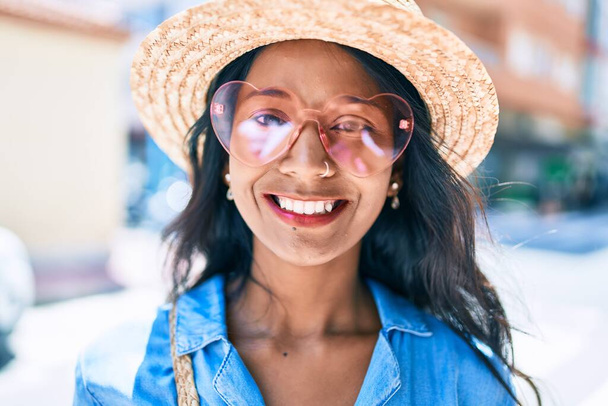 Giovane bella donna indiana che indossa occhiali da sole cuore sorridente felice alla città. - Foto, immagini