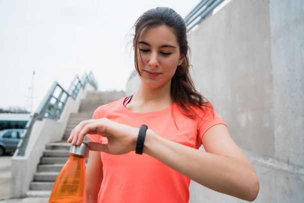 Portrait of a fitness woman checking time on her smart watch. Sport and healthy lifestyle concept. - Foto, Bild