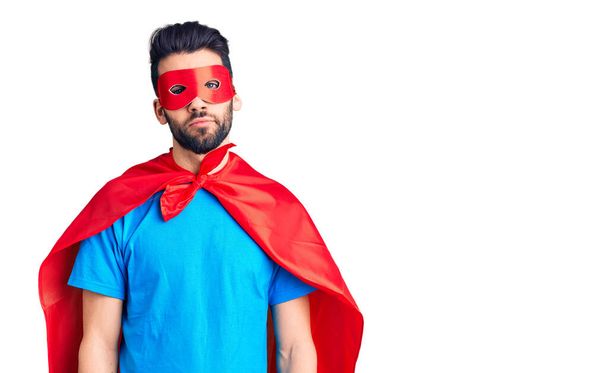 Young handsome man with beard wearing super hero costume relaxed with serious expression on face. simple and natural looking at the camera.  - Photo, Image