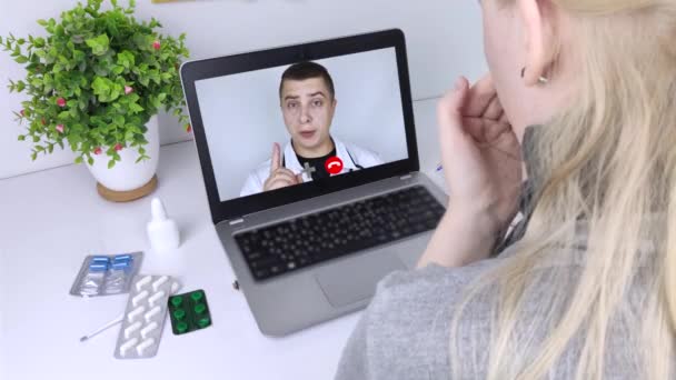 Uma mulher se comunica através de um computador com um médico via link de vídeo. Assistência médica em quarentena. Consulta remota com um terapeuta - Filmagem, Vídeo