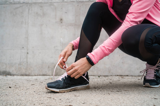 Portrait of an athletic woman  tying her shoelaces and getting ready for jogging outdoors. Sport and healthy lifestyle concept. - Φωτογραφία, εικόνα