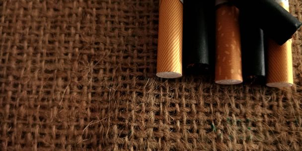 Ruskea ja musta savuke ruskealla säkkimatolla tausta, savukepakkaus, lähikuva savukkeesta - Valokuva, kuva