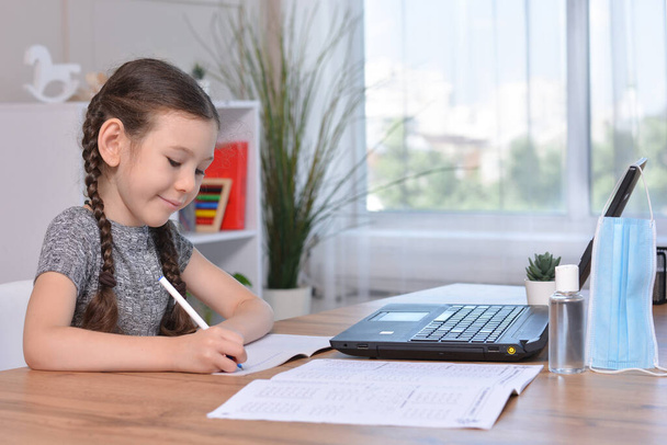 A schoolgirl is doing her homework on a laptop at home or studying in class at a lesson at school.Student safety after covid-19 pandemic. Back to school.Distance learning. - Zdjęcie, obraz