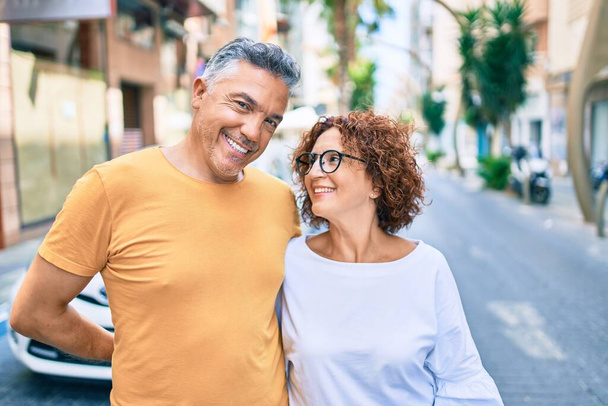 Keski-ikäinen pari hymyilee onnellinen seisoo kadulla kaupungin. - Valokuva, kuva