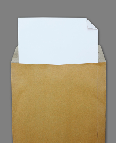 Opened brown envelope with white paper on grey background - Fotó, kép