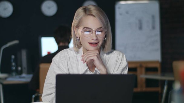 Задоволена бізнес-леді радіє хорошим результатам передній ноутбук в темному офісі
 - Фото, зображення