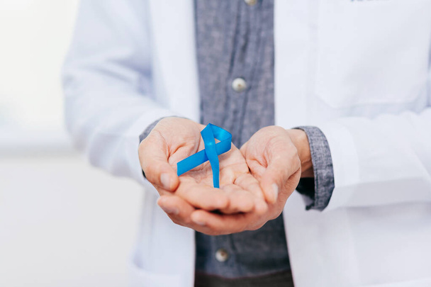 Prostate Cancer Awareness. Doctor man holding light Blue Ribbon for supporting people living and illness. Men Healthcare and World cancer day concept - Fotoğraf, Görsel
