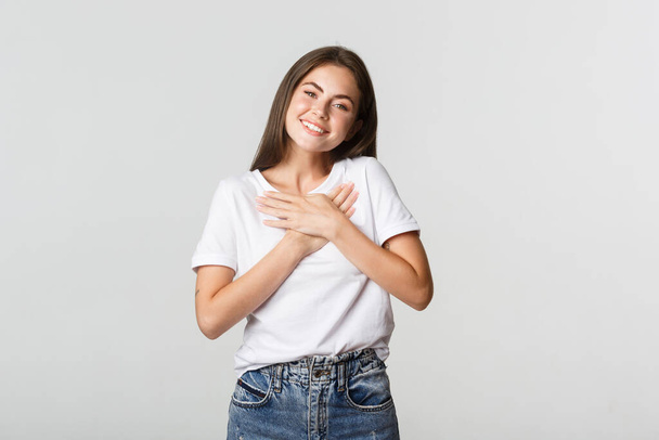 Touched happy young woman smiling, holding hands on chest, feeling thankful - Photo, image
