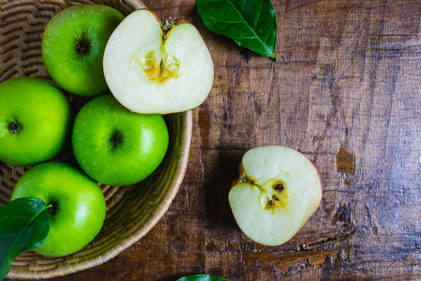 Zelené jablko v košíku na dřevěném stole - Fotografie, Obrázek
