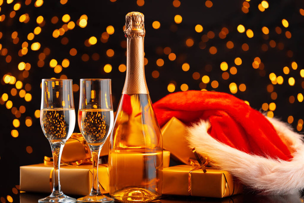 Champagne and Santa Claus hat on blurred garland background - Φωτογραφία, εικόνα