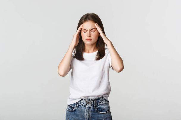 Portrait de femme vertigineuse ou malade touchant la tête et grimaçant de douleur, ayant mal à la tête, souffrant de migraine - Photo, image
