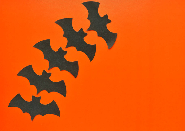Black paper bats lie on an orange background - Photo, Image