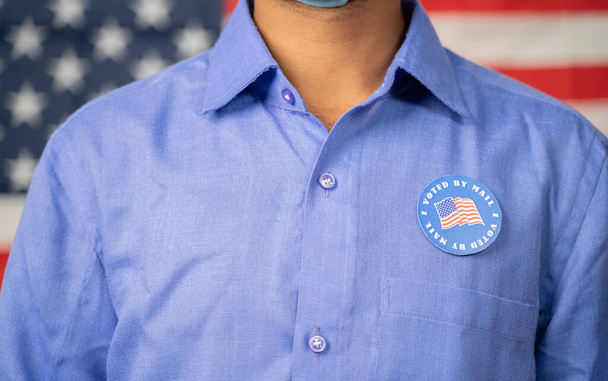 Unrecognizable Man Incollato Ho votato per posta adesiva sul suo adesivo con bandiera degli Stati Uniti come sfondo - Concetto di elezioni negli Stati Uniti, voto per corrispondenza o voto per posta. - Foto, immagini
