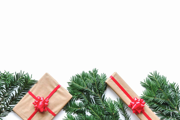 Scatole con regalo e ramoscelli di abete natalizio su una tavola bianca, vista dall'alto, posa piatta, spazio per copiare. - Foto, immagini