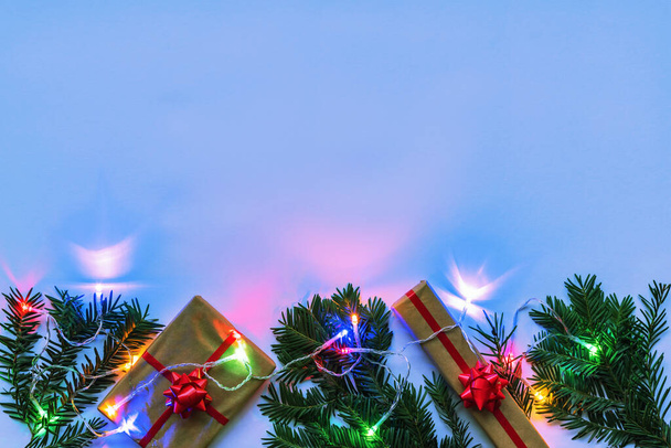 Cajas con regalo y ramitas de abeto de Navidad, guirnalda con luces de colores, fondo de color neón. Vista superior, plano, espacio para copiar. - Foto, imagen
