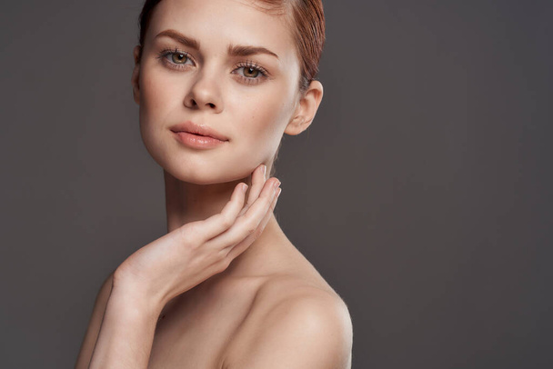 Beautiful woman naked shoulders cosmetics clean skin charm gray background studio - Photo, Image