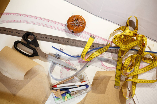 top view of a centimeter yellow, scissors, ruler and other tools of the seamstress. Making clothes. Workplace tailor. - 写真・画像