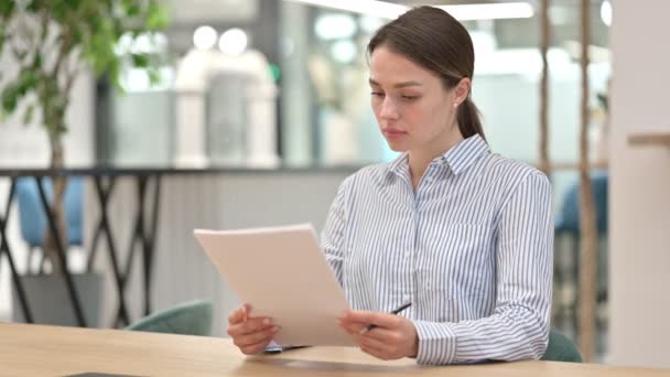 Joven mujer sintiéndose conmocionada leyendo documentos en la oficina  - Imágenes, Vídeo