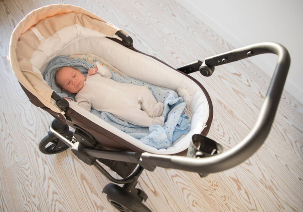 Трохи сплячої новонародженої дитини лежить в колясці
 - Фото, зображення