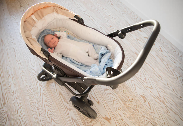 Маленька новонароджена дитина лежить у колясці
 - Фото, зображення