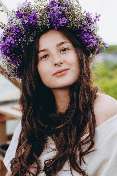 portrait of a pretty young girl dressed in a long linen dress posing for a photo among flowers at a home mini flower farm - 写真・画像