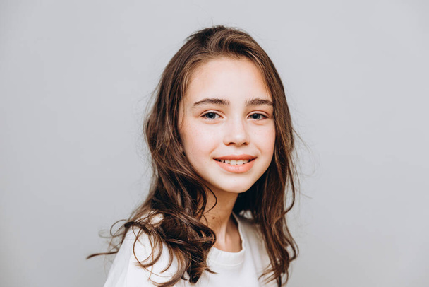 little pretty girl with expressive facial features posing for a photo on a gray background - Fotografie, Obrázek