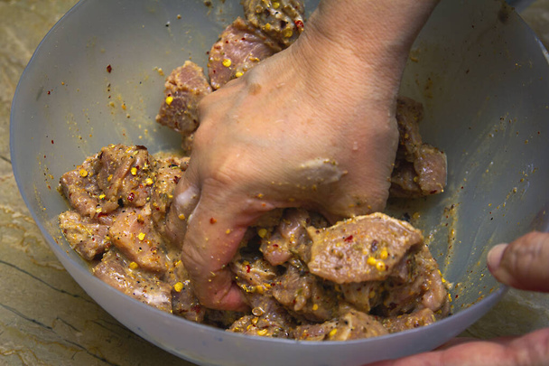 Marineren van vlees in een grote kom met specerijen - Foto, afbeelding