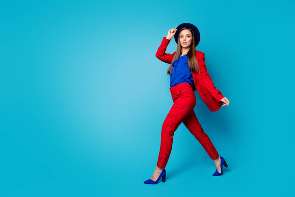 Teljes test profil fotó magabiztos csinos üzletasszony főnök sétál az utcán viselni retro sapka piros ruha blézer nadrág magassarkú elszigetelt kék háttér - Fotó, kép