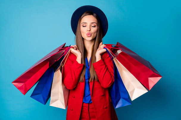 Photo of attractive business lady visiting shopping center holding many packs sending air kisses wear retro cap red suit blouse shirt blazer pants isolated blue color background - 写真・画像